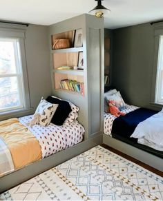 two twin beds in a bedroom with bookshelves on the wall and a rug on the floor