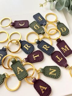 several keychains with letters and numbers are shown on a white surface next to flowers