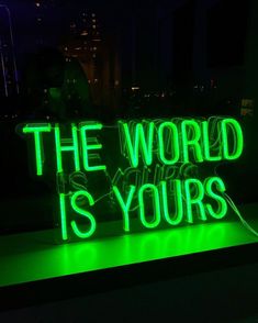 a neon sign that says the world is yours in green and white letters on a black background