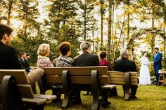 a group of people sitting on top of wooden benches next to each other in front of trees