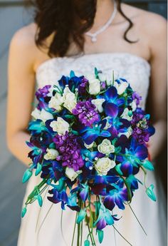 a bride holding a bouquet of purple and white flowers