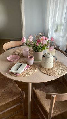 a table with flowers and books on it in the middle of a dining room area