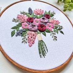 a close up of a embroidery on a hoop with flowers and leaves in the center