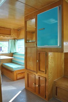 the inside of a small camper with wood paneling and blue glass doors on the windows