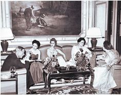 an old black and white photo of four women sitting on a couch in front of a painting