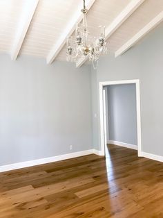 an empty room with wood floors and chandelier