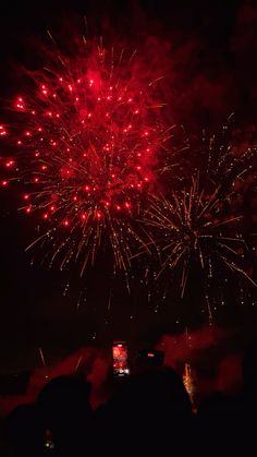 fireworks are lit up in the night sky with red and yellow lights on it's sides