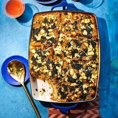 a casserole dish on a blue table with spoons next to it