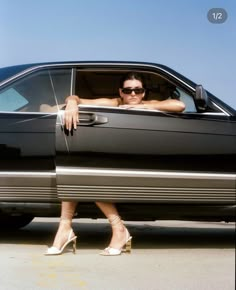 a woman sitting in the drivers seat of a black car