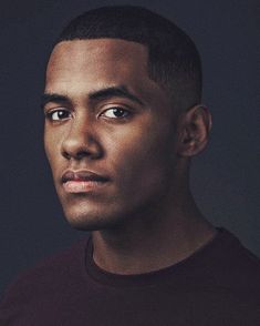 a close up of a person wearing a black t - shirt and looking at the camera