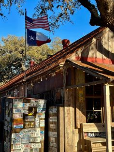 an american flag flying over a small store with signs on the front and side of it