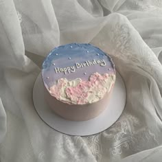 a birthday cake with pink and blue frosting on a white tablecloth covered surface