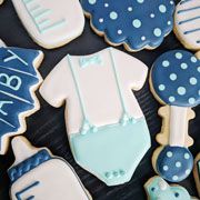 baby shower cookies decorated with blue and white icing on a black tableclothed surface