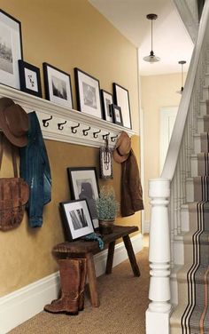 there is a coat rack with hats and pictures on the wall next to stairs in this entryway