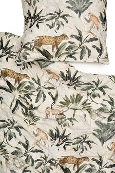 two pillow cases with jungle animals on them, one is white and the other has green leaves