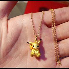 a hand holding a small yellow pokemon necklace