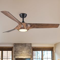 a living room with a ceiling fan and stone fireplace in the center, along with two large windows