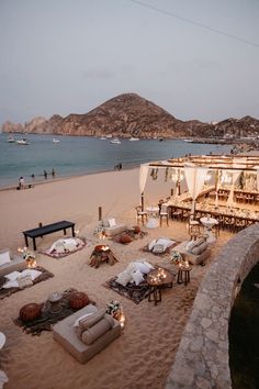 an outdoor seating area is set up on the beach for a wedding ceremony at dusk