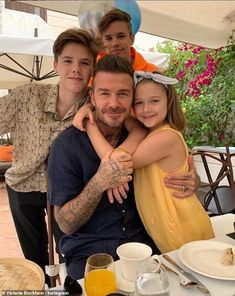 a man and two girls hugging each other in front of an outdoor table with food on it