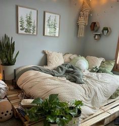 a bed made out of wooden pallets with plants on the side and pictures above it