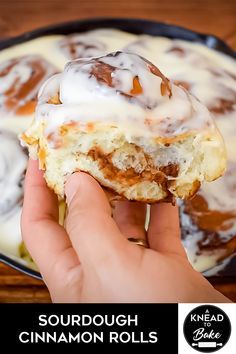 someone is holding up a cinnamon roll with icing on it in front of a skillet