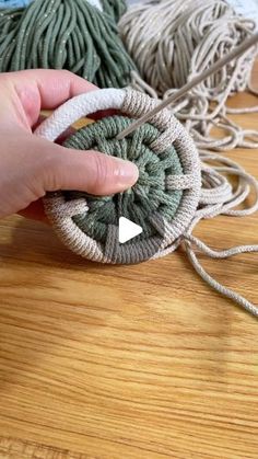 someone is holding yarn in their hand on the wooden floor next to some balls of thread