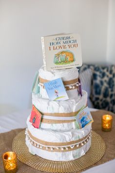 a diaper cake sitting on top of a table next to candles and a book