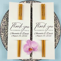 two thank you cards with gold colored chopsticks and a purple orchid on a plate