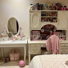 a bedroom with white furniture and pink accessories on the dresser, mirror, and bed