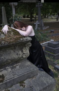 a woman in black dress leaning over a grave