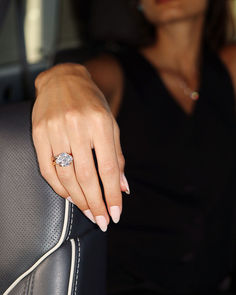 a woman sitting in the back seat of a car holding onto her engagement ring