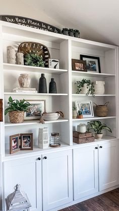 a white bookcase filled with lots of books and vases on top of it