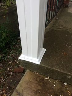 a white post on the side of a sidewalk