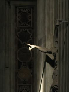 a person reaching up to the side of a building with their arm outstretched in front of them