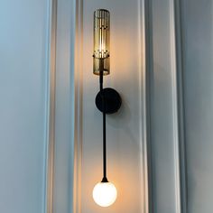 a wall light that is on the side of a building with a lamp attached to it