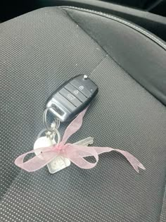 a car keychain with a pink ribbon tied around it's center console