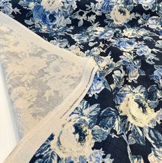 a blue and white floral print fabric on top of a bed sheet with an open window in the background