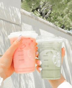 two people holding up cups with drinks in them