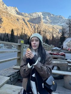 a woman is eating an apple in the mountains