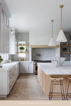 a large kitchen with white cabinets and marble counter tops, along with two stools