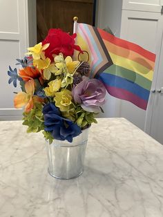 a bouquet of flowers sitting on top of a table next to a rainbow flag in a vase