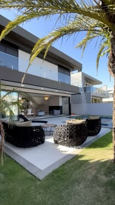 a modern house with palm trees in the foreground and an outdoor dining area on the other side