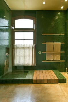 a bathroom with green tile and wooden steps leading to a window that leads into the shower