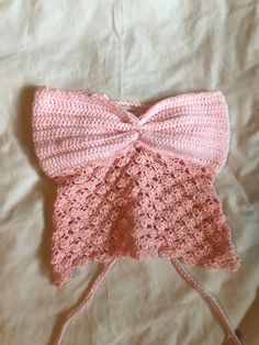 a pink crocheted bow on top of a white sheet