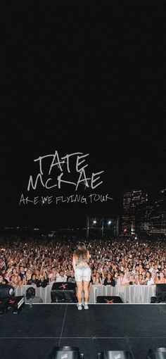 a woman sitting on top of a stage in front of a large group of people