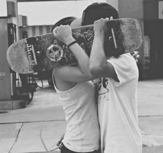 two people holding up skateboards in front of their faces with one person covering the other's eyes