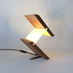 a wooden table lamp with a white light on the top and an electric cord attached to it