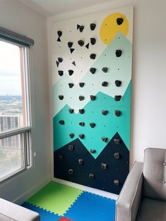 a room with a climbing wall in the corner and a gray chair next to it