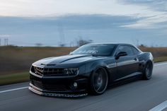 a black camaro is driving down the road