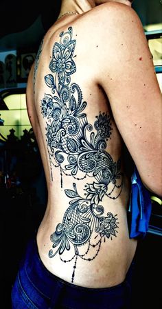 the back of a woman's body with an intricate tattoo design on her left side